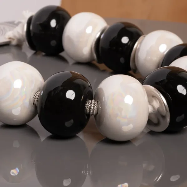 détail d'un komboloi décoratif en céramique irisée blanche et noire, entre tradition unique et élégance moderne - une création artisanale Photyne.