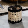 Photophore artisanal en verre, habillé de rotin et de coton noir, pour une ambiance douce et apaisante – l'art de la table selon Photyne
