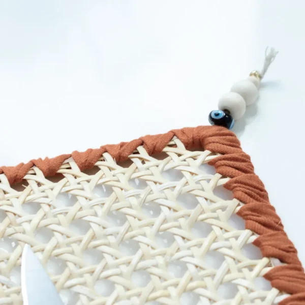 Focus sur un Set de table en rotin naturel, tresse de coton terracotta et perles de bois, parfait pour une table chic et chaleureuse – une création Photyne.