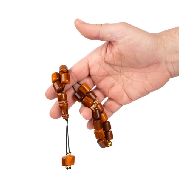 Main tenant un komboloi grec artisanal avec des perles cylindriques dans les teintes marron - tradition grecque et savoir faire français - Photyne