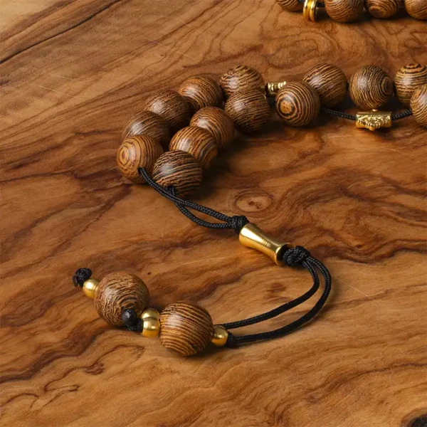 Vue rapprochée du komboloi en bois de wengé avec son fil noir résistant et ses ornements métalliques dorés, ou comment se relaxer avec style - une création artisanale Photyne