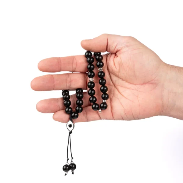 main ouverte sur un komboloi grec noir en perles d’ébène et son médaillon en forme l'oeil protecteur - Photyne