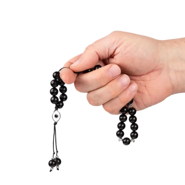 main tenant un komboloi grec en perles d’ébène et médaillon représentant l'oeil protecteur - une création Photyne
