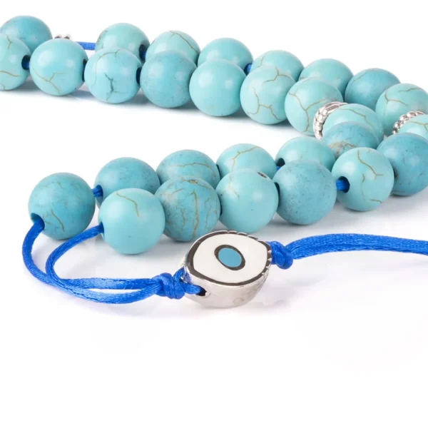 Komboloï grec artisanal , perles de couleur turquoise avec des nervures naturelles, agrémenté d'éléments en métal argenté et d'un pendentif représentant l'œil protecteur - une création Photyne