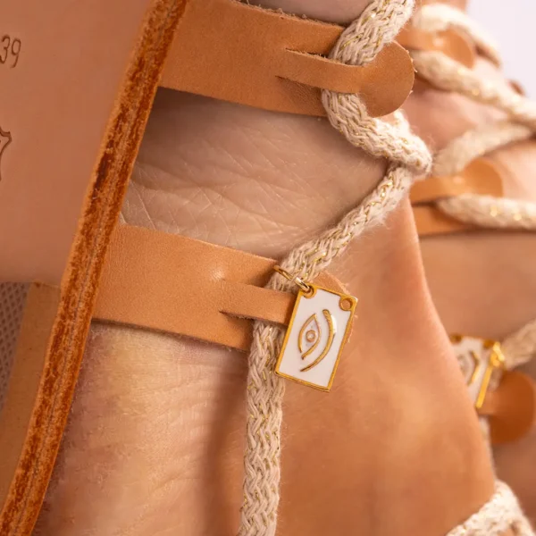 Gros plan sur la sandale montante Photyne faite main en Grèce et son médaillon protecteur œil grec