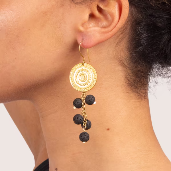 plan serré sur les boucles d'oreilles en perles de lave et médaillon or mat- modèle Fira par Photyne