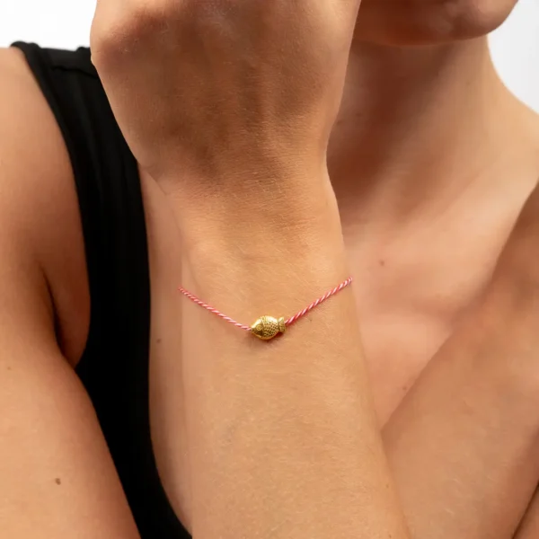 Focus sur bracelet traditionnel grec, en fil torsadé blanc et rouge orné d’un poisson doré à l’or 24K - Photyne