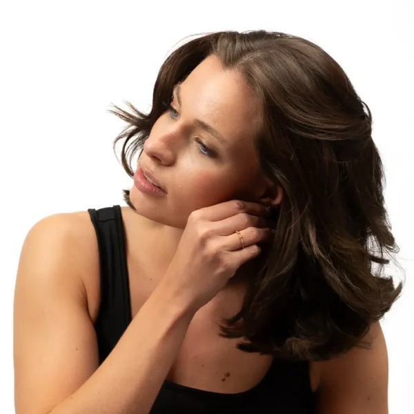 Jeune fille enfilant une boucle d'oreille composant le coffret cadeau trois bijoux uniques : bracelet et bague et puces d'oreilles - une création Photyne