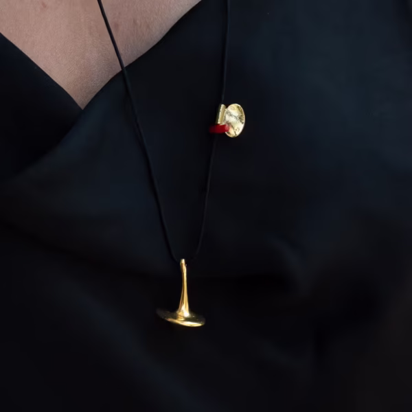 Bijou Svoura, sautoir raffiné avec pendentif toupie et détail corail rouge symbolique, savoir faire artisanal Photyne.
