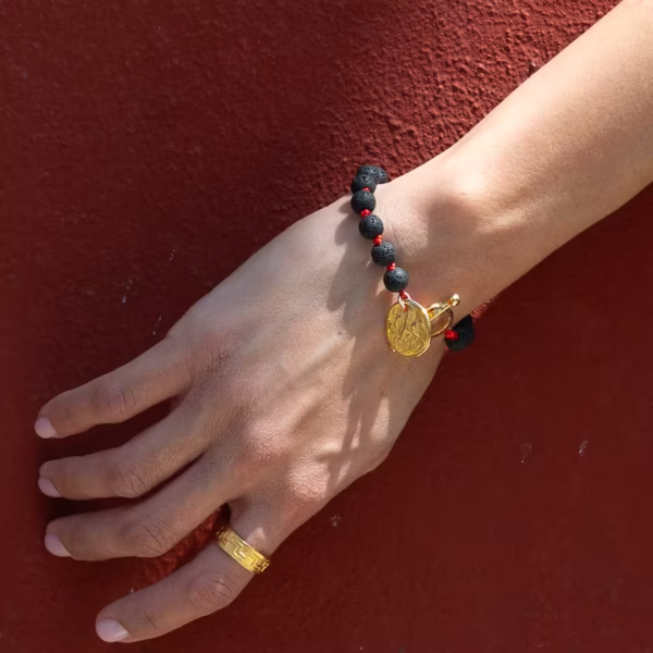 Focus sur le bracelet Fira, Bijou inspiré de Santorin, perles de lave noire et médaille dorée, une création originale Photyne.