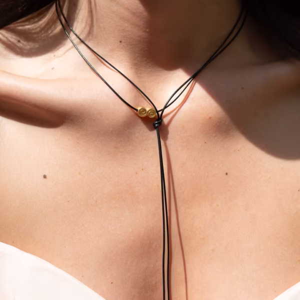 Sautoir-Ras du cou- modèle Ionos lacet noir et breloque dorée en forme de volute -un Bijou Photyne