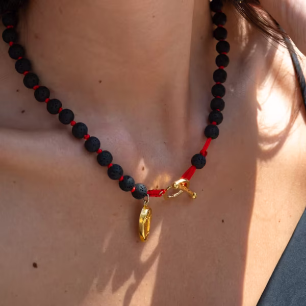 Bijou inspiré de Santorin, collier en perles de lave noire et breloque dorée cycladique, une création originale Photyne.