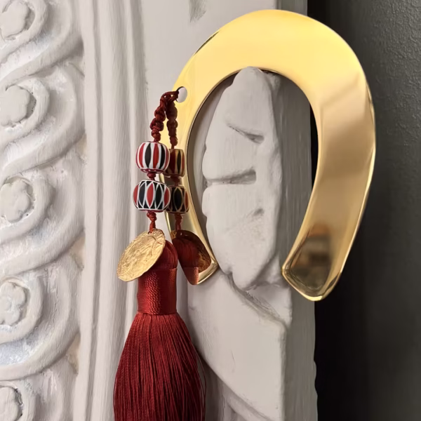 alisman artisanal porte chance, fer à cheval doré traditionnel avec pompon terracotta, éloigne les énergies négatives, une création Photyne.