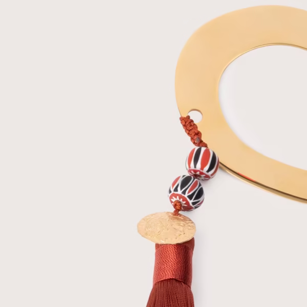 Talisman protecteur fer à cheval doré, pompon terracotta chaleureux et médaille dorée, symbole de sagesse et chance, une création originale Photyne