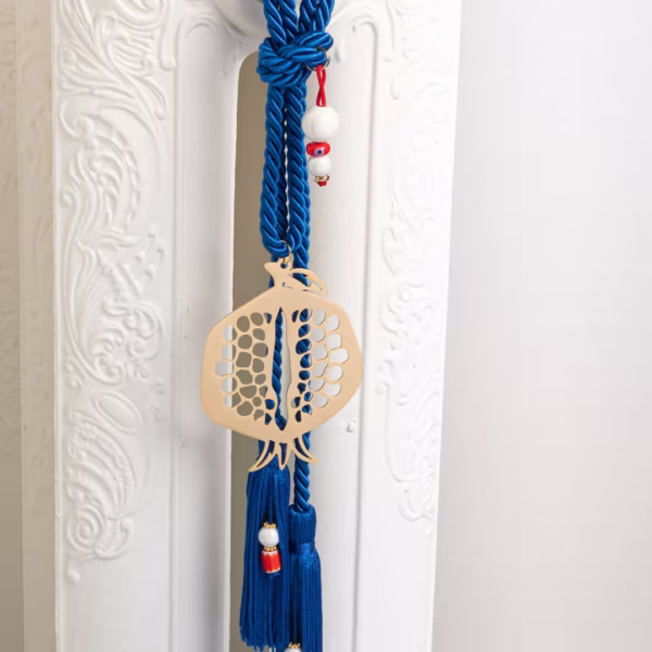 Objet porte chance artisanal, grenade dorée ajourée et cordon bleu avec pompons, symbole de renouveau et énergie positive, savoir faire artisanal Photyne.
