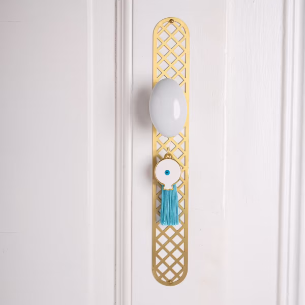 Porte-bonheur grenade grecque en métal doré avec œil protecteur et pompon turquoise, symbole de chance et protection, une création Photyne.