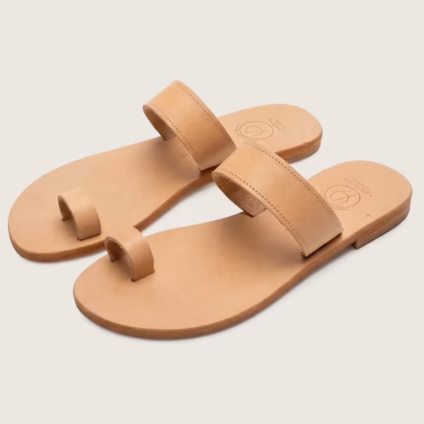 Sandales en cuir grecques plates en cuir naturel, au design épuré avec bride large et entredoigt, vue en studio sur fond clair - modèle Chania - Photyne