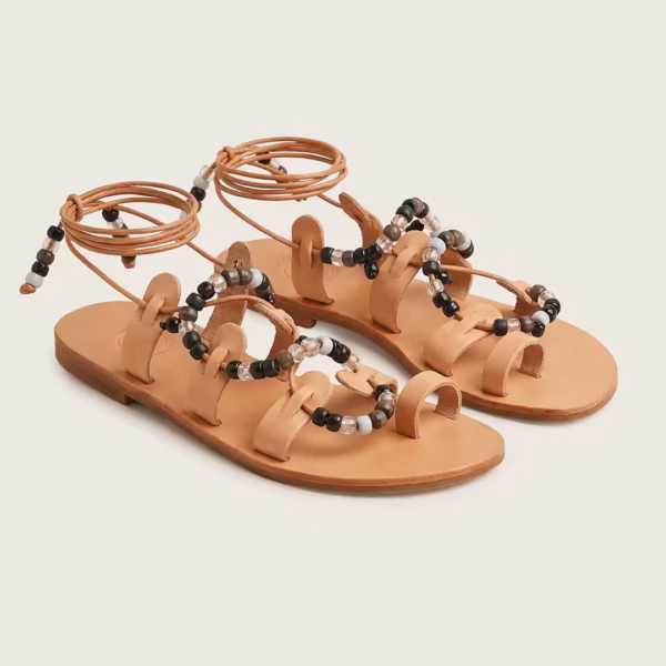 Paire de sandales grecques artisanales de style gladiateur en cuir naturel à lacets montants, ornées de perles noires et transparentes, présentées à plat sur fond clair - modèle margarita noire -Photyne