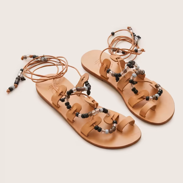 Sandales grecques de type gladiateur en cuir naturel à lacets montants, ornées de perles noires, transparentes et brun fumé, présentées à plat sur fond clair - modèle margarita noire -Photyne