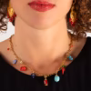 gros plan sur un ras du cou chaine dorée et pendentifs corail et céramique - un bijou artisanal Photyne