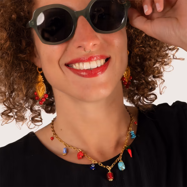 Collier doré avec pendentifs colorés porté par une femme avec des boucles d'oreilles pendantes perles de corail - Photyne