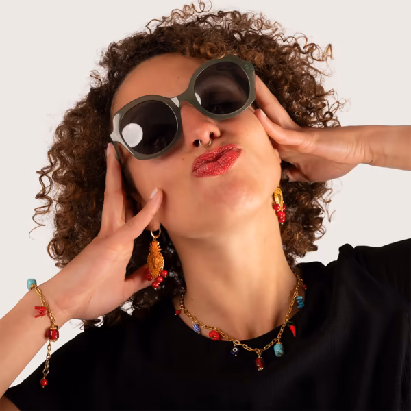 Collier doré avec pendentifs colorés porté par une femme avec des boucles d'oreilles dorées et colorées - Photyne
