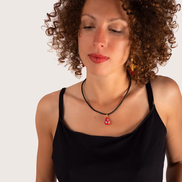 Ras du cou cordon cuir noir et médaillon rouge à motifs porté par une femme aux cheveux bouclés - modèle Leda par Photyne