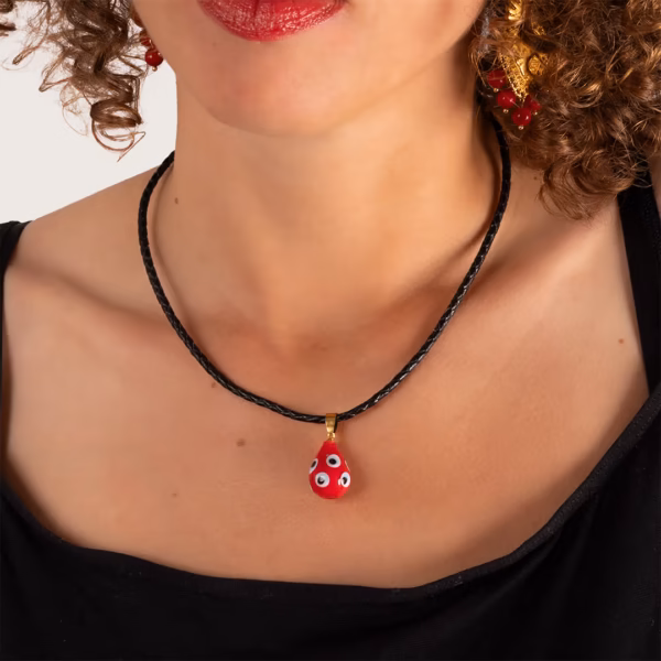 Collier médaillon rouge à motifs porté par une femme aux cheveux bouclés