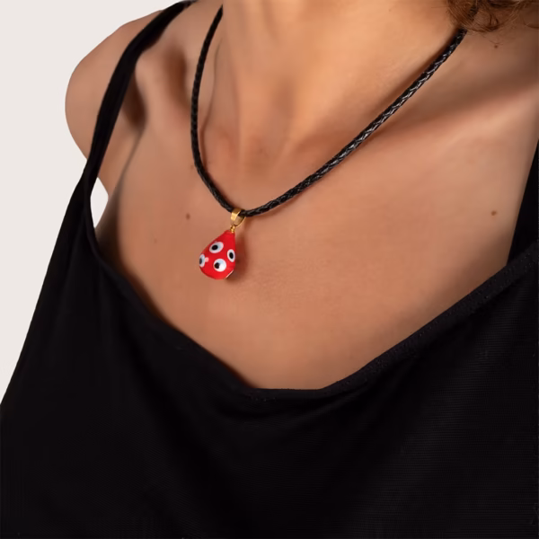 Collier avec pendentif rouge à motifs d'yeux porté sur un haut noir - un bijou Photyne