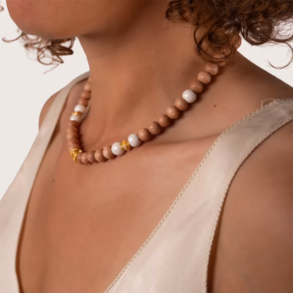 collier de perles en bois naturel et céramique blanches avec détails dorés porté par une femme - modèle Eleni - Photyne