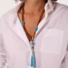 collier de perles de bois de bayong et de perles de céramiques bleues - éléments dorés et pompon turquoise porté par une femme sur une chemise blanche entrouverte