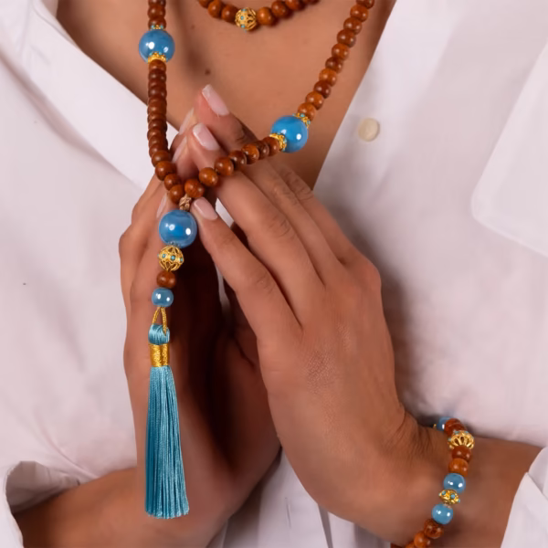 collier Nyx - perles en bois et perles bleues et or et pompon turquoise porté sur chemise blanche - Photyne