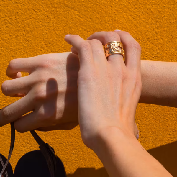 bague artisanale dorée finement ciselée et portée sur le doigt d'une femme - un bijou réalisé en France par Photyne.